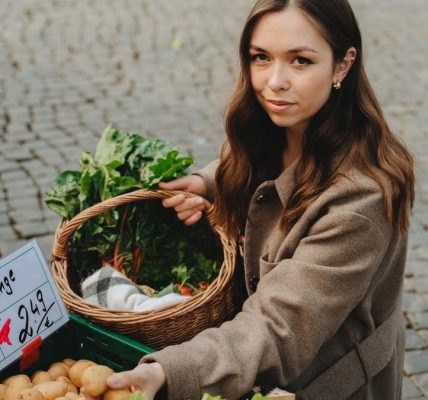 Young woman shopping at Erfurt farmers market, holding basket with fresh vegetables. Capturing local shopping culture.