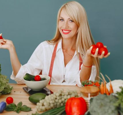 Healthy lifestyle concept with woman holding tomatoes and surrounded by fresh vegetables in a studio setting.